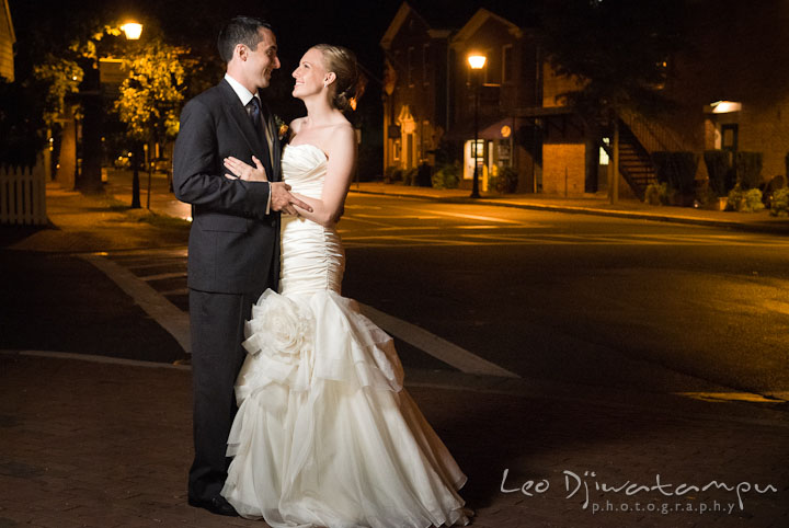 Bride and groom holding each other with city lights in the background. The Tidewater Inn Wedding, Easton Maryland, reception photo coverage of Kelsey and Jonnie by wedding photographers of Leo Dj Photography.