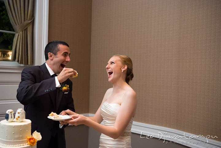 Bride and groom laughing while feeding each other wedding cake. The Tidewater Inn Wedding, Easton Maryland, reception photo coverage of Kelsey and Jonnie by wedding photographers of Leo Dj Photography.