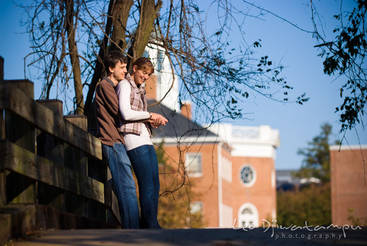 Engaged guy hugging his fiancée on a bridge. Pre-wedding engagement photo session at Washington College and Chestertown, Maryland, by wedding photographer Leo Dj Photography.