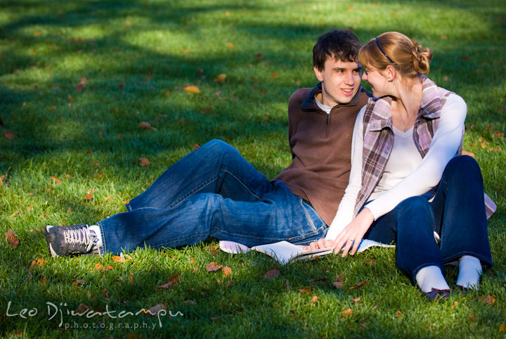 Engaged couple reading a book on the lawn. Pre-wedding engagement photo session at Washington College and Chestertown, Maryland, by wedding photographer Leo Dj Photography.