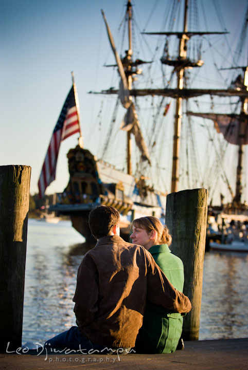 Engaged guy embracing his fiancee, overlooking at an old ship. Pre-wedding engagement photo session at Washington College and Chestertown, Maryland, by wedding photographer Leo Dj Photography.