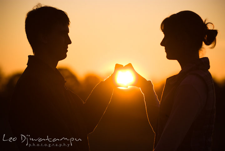 Engaged guy and girl making a heart shape around the sun with their hands. Pre-wedding engagement photo session at Washington College and Chestertown, Maryland, by wedding photographer Leo Dj Photography.