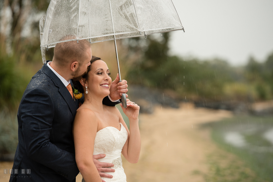 Chesapeake Bay Beach Club Bride and Groom cuddling under the rain photo by Leo Dj Photography.