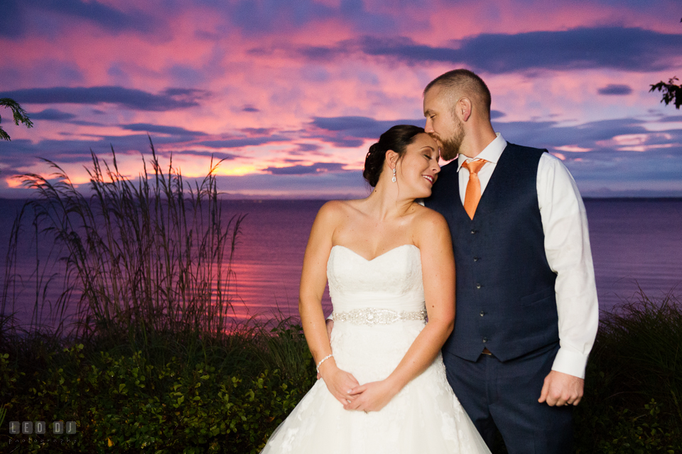 Chesapeake Bay Beach Club Groom kissed Bride by the water under the beautiful sunset sky photo by Leo Dj Photography.