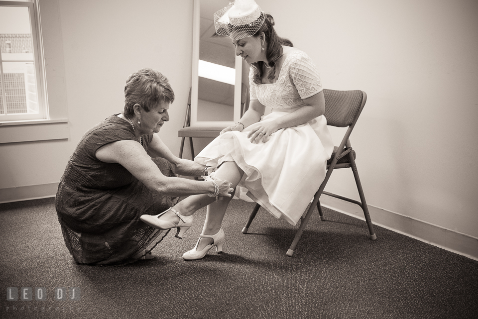 Mother of the Bride putting on garter on daughter's leg. Fisherman's Inn, Safe Harbor Church, Kent Island, Eastern Shore Maryland, wedding reception and ceremony photo, by wedding photographers of Leo Dj Photography. http://leodjphoto.com