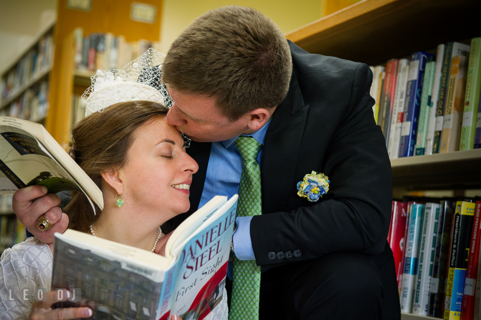 Groom kissed Bride while reading book in the library. Fisherman's Inn, Safe Harbor Church, Kent Island, Eastern Shore Maryland, wedding reception and ceremony photo, by wedding photographers of Leo Dj Photography. http://leodjphoto.com