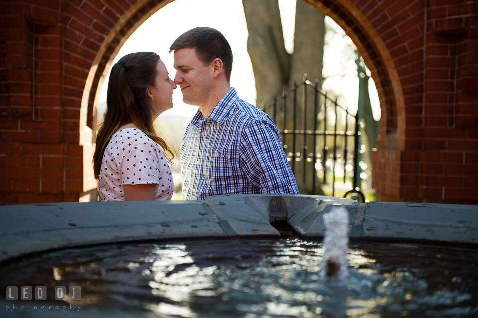Engaged couple cuddling by a fountain inside a red brick structure. Washington DC pre-wedding engagement photo session at the Capitol Hill and the Mall, by wedding photographers of Leo Dj Photography. http://leodjphoto.com