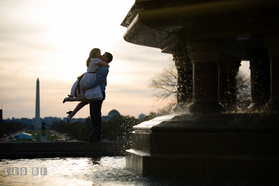 Engaged couple kissing by the water fountain with the Washington Monument in the background during sunset. Washington DC pre-wedding engagement photo session at the Capitol Hill and the Mall, by wedding photographers of Leo Dj Photography. http://leodjphoto.com