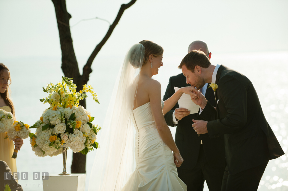 Groom kissing Bride's hand during the ceremony. Kent Island Maryland Chesapeake Bay Beach Club wedding photo, by wedding photographers of Leo Dj Photography. http://leodjphoto.com