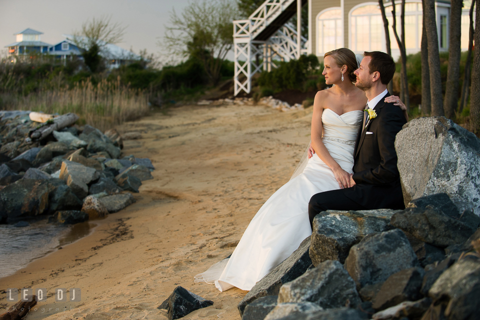 Bride and Groom at the beach sitting together on the rocks overlooking at the water. Kent Island Maryland Chesapeake Bay Beach Club wedding photo, by wedding photographers of Leo Dj Photography. http://leodjphoto.com