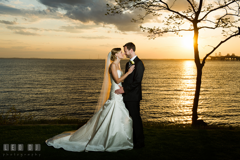 Bride and Groom embracing each other with the sunset on the water in the background. Kent Island Maryland Chesapeake Bay Beach Club wedding photo, by wedding photographers of Leo Dj Photography. http://leodjphoto.com