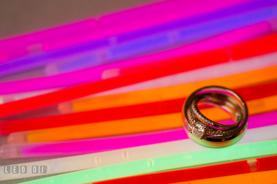 Bride's and Groom's diamond engagement ring and wedding bands on various colored glow sticks. Kent Island Maryland Chesapeake Bay Beach Club wedding photo, by wedding photographers of Leo Dj Photography. http://leodjphoto.com