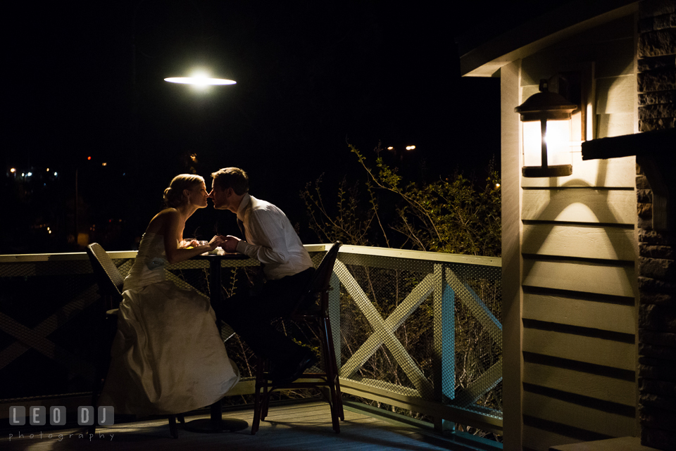 Bride and Groom sitting by a table at an outdoor terrace in the evening. Kent Island Maryland Chesapeake Bay Beach Club wedding photo, by wedding photographers of Leo Dj Photography. http://leodjphoto.com