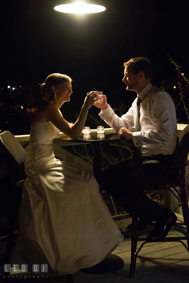 Bride and Groom sitting outside on the terrace, toasting together. Kent Island Maryland Chesapeake Bay Beach Club wedding photo, by wedding photographers of Leo Dj Photography. http://leodjphoto.com