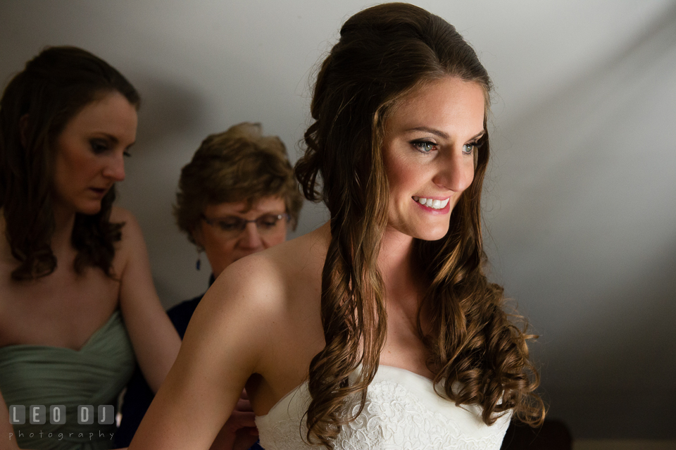 Bride smiling while Mother and Maid of Honor helps button up the wedding dress. Historic Inns of Annapolis Maryland, Governor Calvert House wedding, by wedding photographers of Leo Dj Photography. http://leodjphoto.com