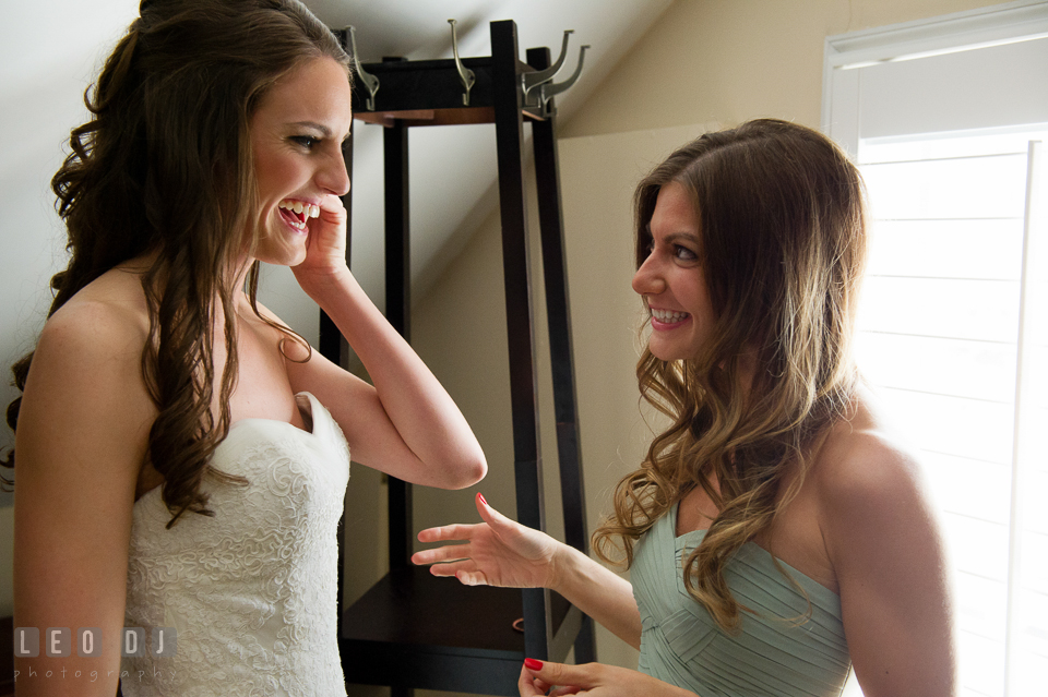 Bride putting on her earring and laughing with her bridesmaid. Historic Inns of Annapolis Maryland, Governor Calvert House wedding, by wedding photographers of Leo Dj Photography. http://leodjphoto.com