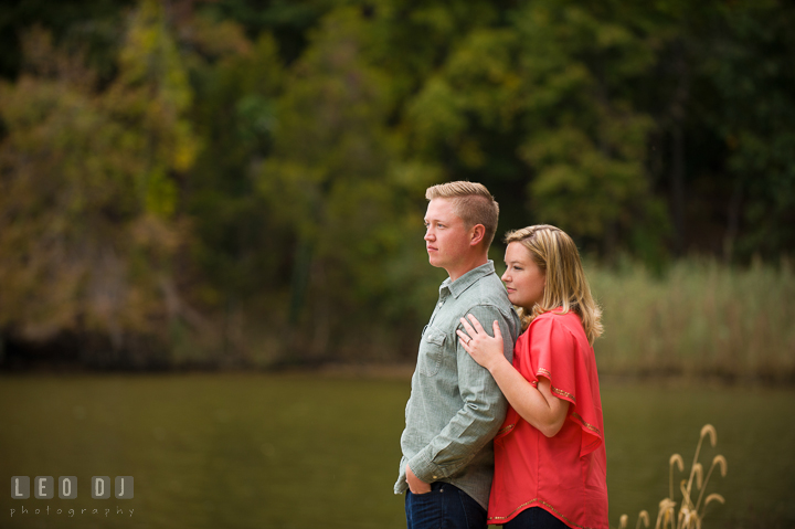 Engaged girl hugging her fiancé from behind, enjoying the view. Chestertown Eastern Shore Maryland pre-wedding engagement photo session by the water, by wedding photographers of Leo Dj Photography. http://leodjphoto.com
