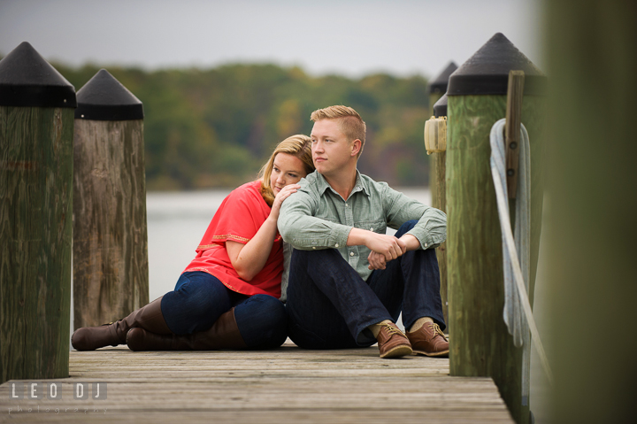 Engaged girl sitting on the boat dock leaning on her fiancé. Chestertown Eastern Shore Maryland pre-wedding engagement photo session by the water, by wedding photographers of Leo Dj Photography. http://leodjphoto.com
