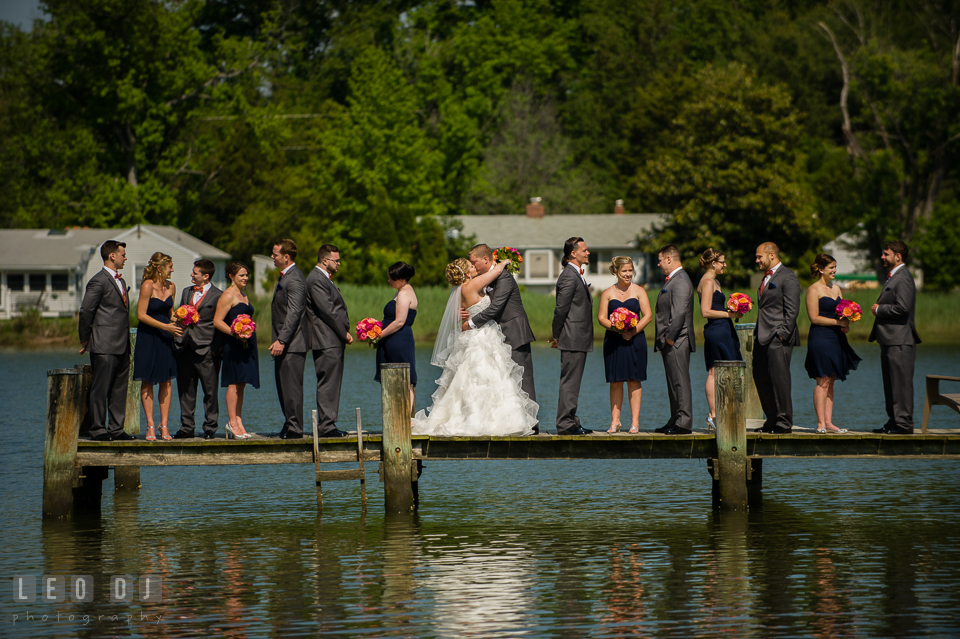 Bride and Groom kissing while the wedding party is on the dock . Kent Manor Inn, Kent Island, Eastern Shore Maryland, wedding ceremony and getting ready photos, by wedding photographers of Leo Dj Photography. http://leodjphoto.com