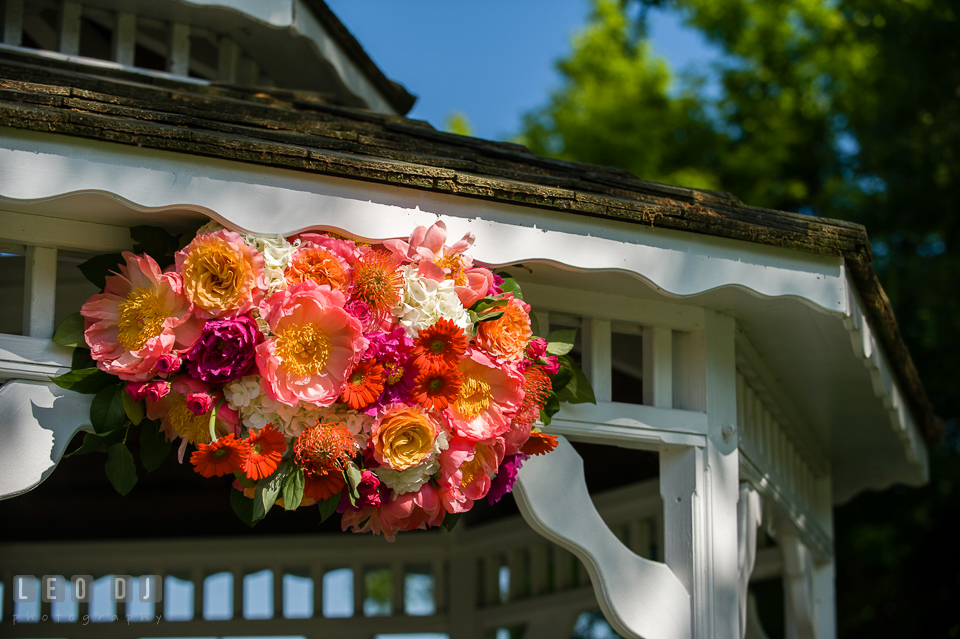 Floral decor of bold and vibrant colored peonies, roses, gerberas, and proteas on gazebo designed florist by Intrigue Design and Decor. Kent Manor Inn, Kent Island, Eastern Shore Maryland, wedding ceremony and getting ready photos, by wedding photographers of Leo Dj Photography. http://leodjphoto.com