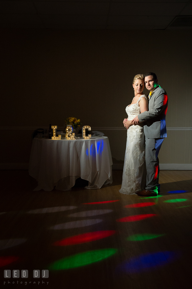 Bride and Groom posing by their sweetheart table lighted with colorful lights from the DJ. Maryland Yacht Club wedding at Pasadena Maryland, by wedding photographers of Leo Dj Photography. http://leodjphoto.com