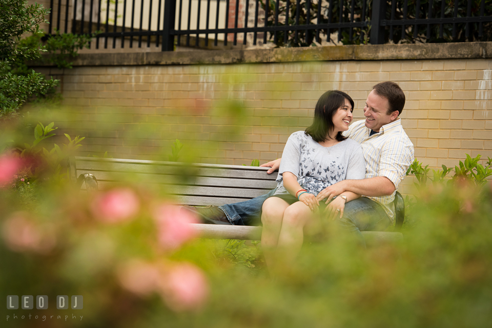 Engaged couple sitting together on a bench, laughing. Annapolis Eastern Shore Maryland pre-wedding engagement photo session at downtown, by wedding photographers of Leo Dj Photography. http://leodjphoto.com