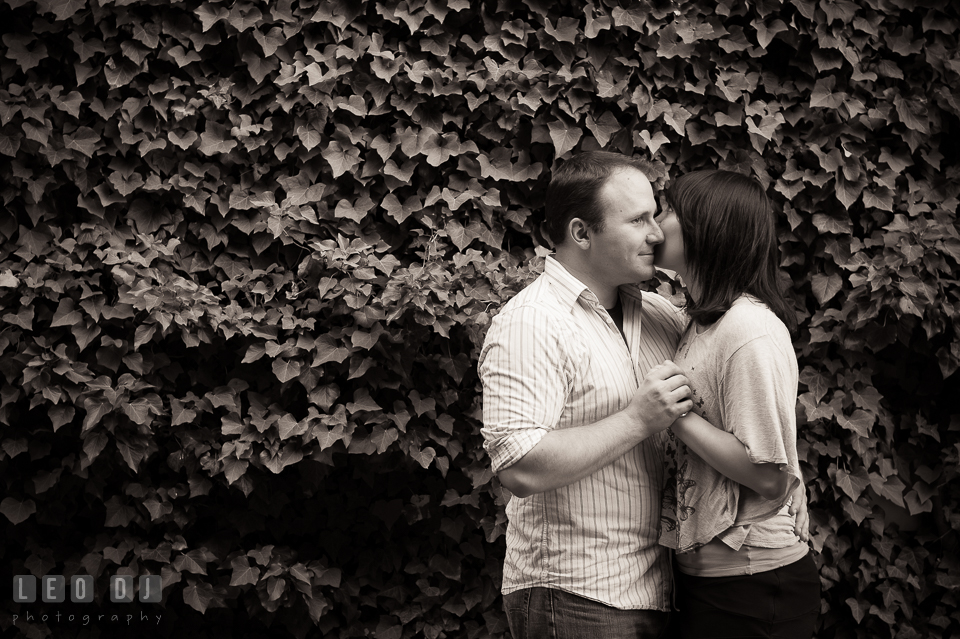 Engaged man kissed by his fiancee, by a wall filled with ivy. Annapolis Eastern Shore Maryland pre-wedding engagement photo session at downtown, by wedding photographers of Leo Dj Photography. http://leodjphoto.com