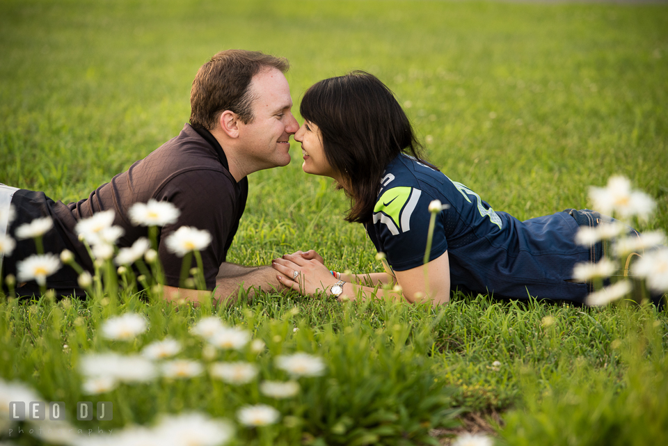 Engaged couple lying on the ground holding hands and smiling together. Quiet Waters Park Annapolis Maryland pre-wedding engagement photo session, by wedding photographers of Leo Dj Photography. http://leodjphoto.com