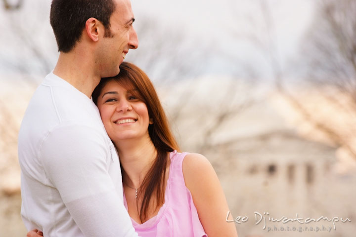 Engaged guy hugging his fiancée, laughing. Jefferson Memorial in the background. Washington DC Tidal Basin Cherry Blossom Pre-Wedding Engagement Photo Session by Wedding Photographer Leo Dj Photography