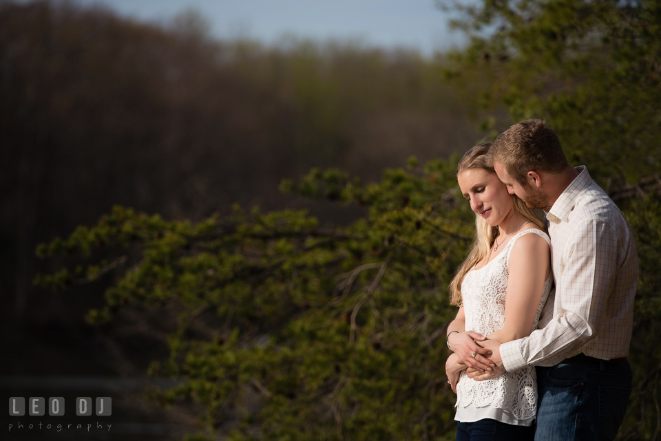 Engaged couple cuddling by the river. Quiet Waters Park Annapolis Maryland pre-wedding engagement photo session, by wedding photographers of Leo Dj Photography. http://leodjphoto.com