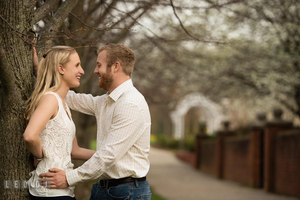 Engaged couple embracing and laughing together by a tree. Quiet Waters Park Annapolis Maryland pre-wedding engagement photo session, by wedding photographers of Leo Dj Photography. http://leodjphoto.com