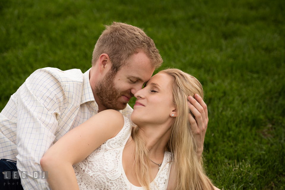 Engaged girl cuddling on the grass with her fiance. Quiet Waters Park Annapolis Maryland pre-wedding engagement photo session, by wedding photographers of Leo Dj Photography. http://leodjphoto.com