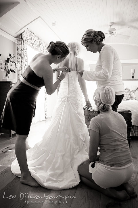 Bride getting help from maid of honor and bridesmaids putting on (lacing up and buttonning) the wedding dress, wedding gown. Annapolis Wedding Photographer, Wedding at St Mary's Catholic Church Annapolis Maryland.