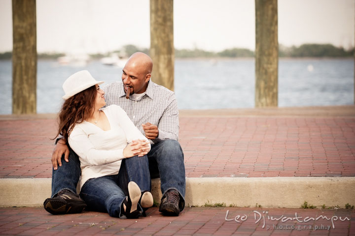 Guy smoking cigar, talking with his fiancée by the water. Annapolis Maryland USNA Pre-Wedding Engagement Photo Session by wedding photographer Leo Dj Photography