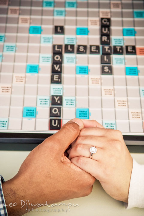 I love you on scrabble board. Engaged couple holding hands, showing engagement ring. Annapolis Maryland USNA Pre-Wedding Engagement Photo Session by wedding photographer Leo Dj Photography