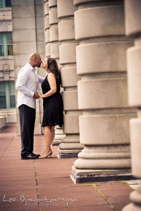 Engaged couple almost kissed by tall USNA building columns. Annapolis Maryland USNA Pre-Wedding Engagement Photo Session by wedding photographer Leo Dj Photography