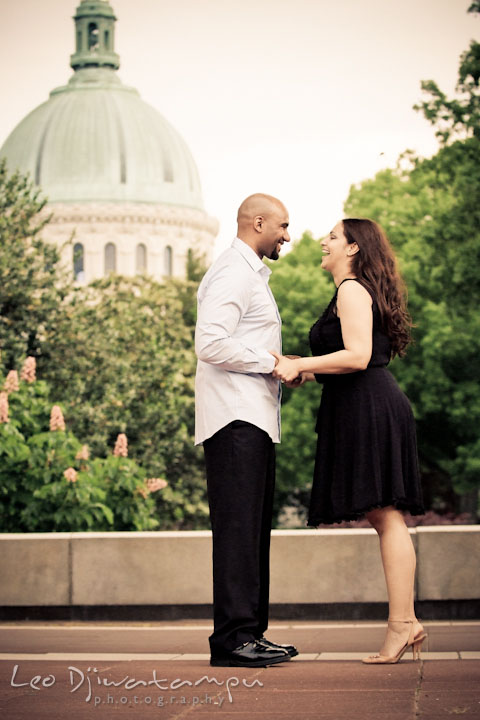 Engaged couple laughing with USNA chapel dome in the background. Annapolis Maryland USNA Pre-Wedding Engagement Photo Session by wedding photographer Leo Dj Photography