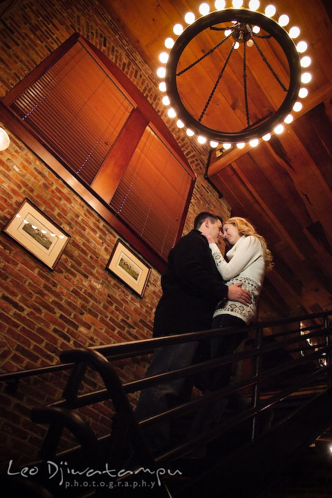 Engaged couple cuddling on the stairs, under a circular light. Old Town Alexandria Virgina Pre-wedding Engagement Photo Session Photographer, Leo Dj Photography