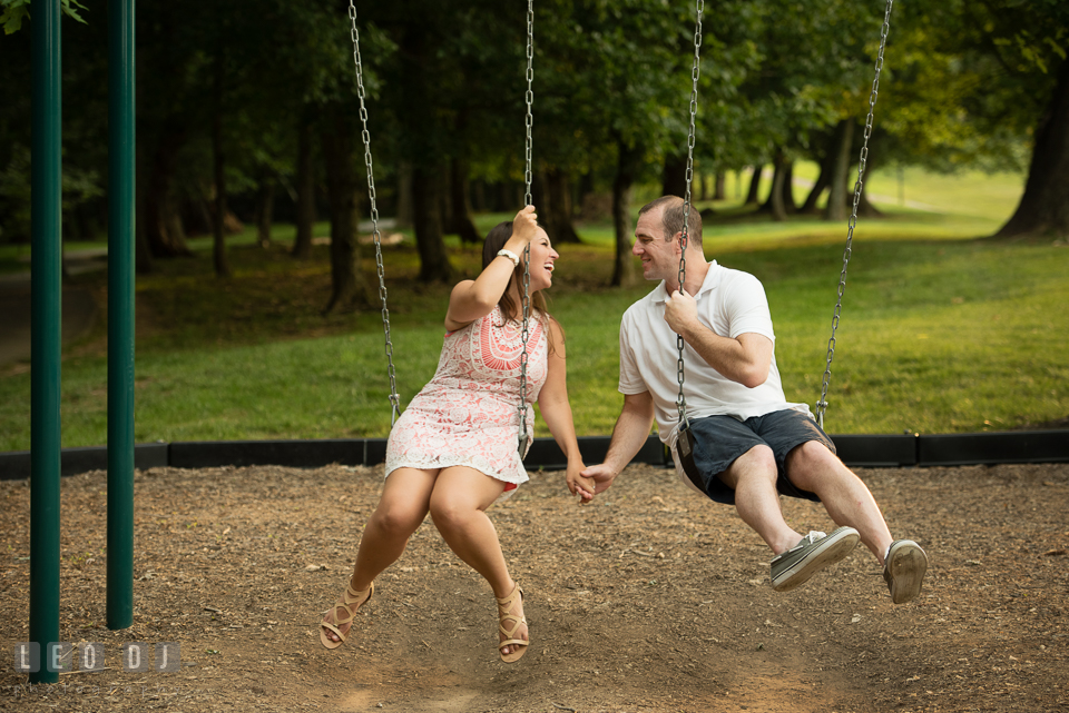 Engaged couple holding hands while playing on the swing. Leesburg Virginia pre-wedding engagement photo session at River Creek Club, by wedding photographers of Leo Dj Photography. http://leodjphoto.com