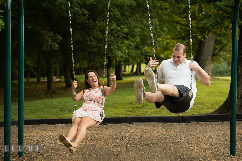 Engaged girl playing swing with her fiance, having fun and laughing. Leesburg Virginia pre-wedding engagement photo session at River Creek Club, by wedding photographers of Leo Dj Photography. http://leodjphoto.com