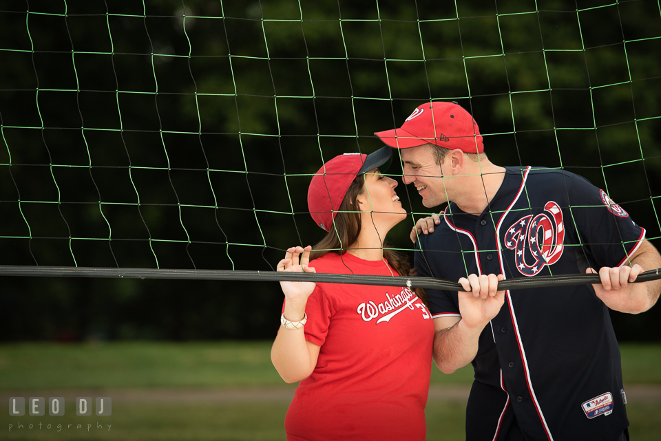 Engaged couple with MLB Washington Nationals jersey and cap almost kissing. Leesburg Virginia pre-wedding engagement photo session at River Creek Club, by wedding photographers of Leo Dj Photography. http://leodjphoto.com