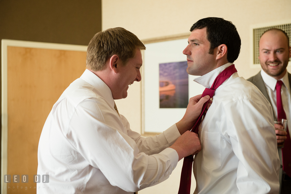 Groom helps Best Man with his tie. Hyatt Regency Chesapeake Bay wedding at Cambridge Maryland, by wedding photographers of Leo Dj Photography. http://leodjphoto.com