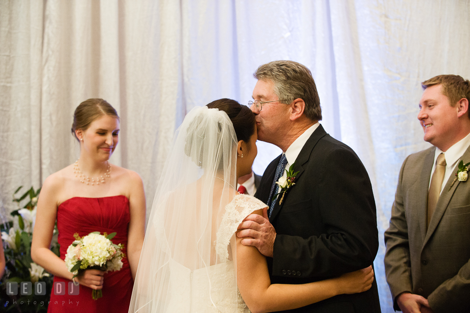 Father kissed Bride while giving away daughter during wedding ceremony. Hyatt Regency Chesapeake Bay wedding at Cambridge Maryland, by wedding photographers of Leo Dj Photography. http://leodjphoto.com