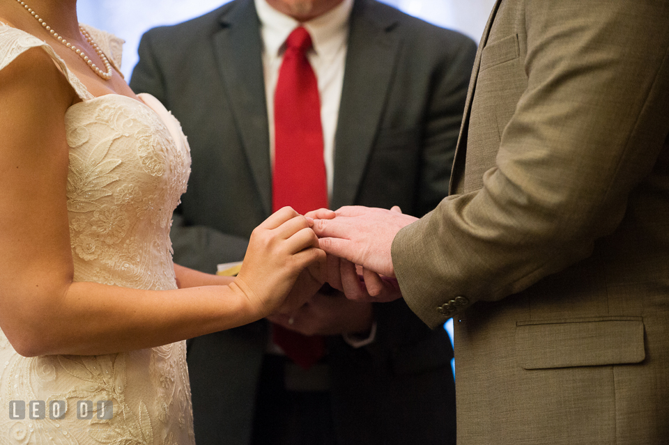 Bride putting on wedding band on Groom's finger during wedding ceremony. Hyatt Regency Chesapeake Bay wedding at Cambridge Maryland, by wedding photographers of Leo Dj Photography. http://leodjphoto.com