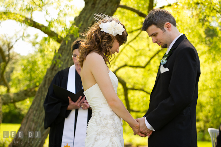 Bride and Groom holding hands together and bow their heads while officiant reads a prayer. Ostertag Vistas wedding ceremony photos at Myersville, Maryland by photographers of Leo Dj Photography. http://leodjphoto.com