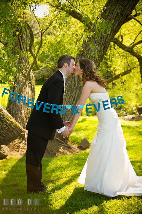 Bride and Groom kissing underneath a tree with Forevers and Evers banner. Ostertag Vistas wedding ceremony photos at Myersville, Maryland by photographers of Leo Dj Photography. http://leodjphoto.com