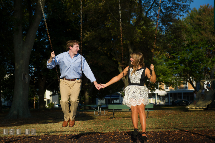 Engaged couple playing swing together and laughing. Oxford, Eastern Shore Maryland pre-wedding engagement photo session, by wedding photographers of Leo Dj Photography. http://leodjphoto.com