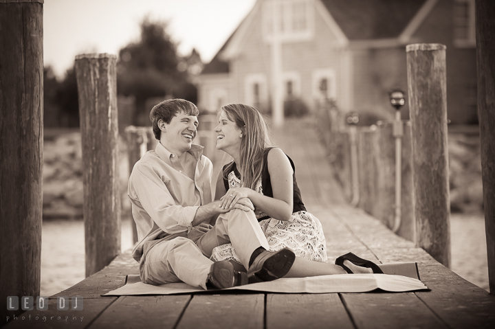 Engaged guy and his fiancée sitting on a boat dock laughing. Oxford, Eastern Shore Maryland pre-wedding engagement photo session, by wedding photographers of Leo Dj Photography. http://leodjphoto.com