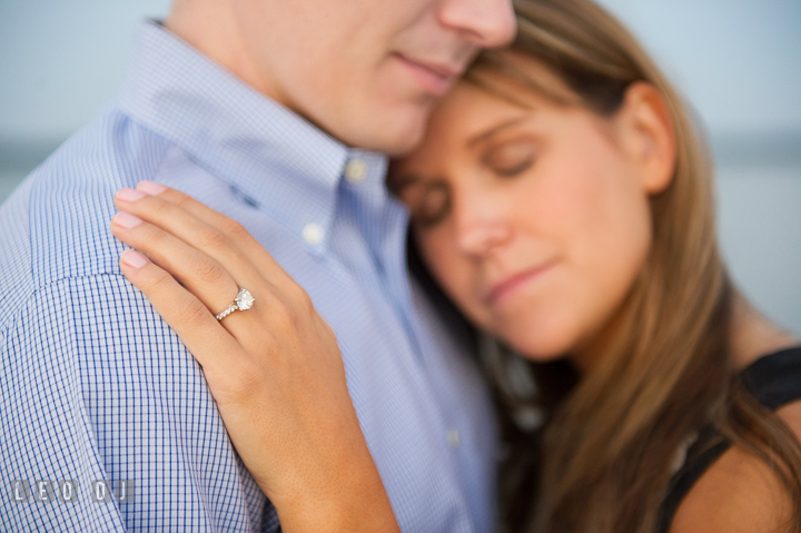 Engaged girl leaning her head on fiancé's chest and showing engagement ring. Oxford, Eastern Shore Maryland pre-wedding engagement photo session, by wedding photographers of Leo Dj Photography. http://leodjphoto.com