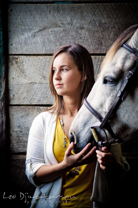 Girl holding horse, looking outside of stall. Annapolis Kent Island Maryland High School Senior Portrait Photography with Horse Pet by photographer Leo Dj